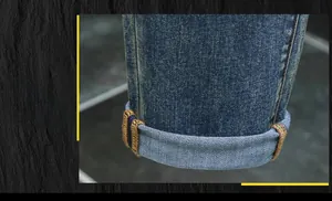 Close-up of classic blue denim jeans cuff showing colorful stitching and rolled hem detail