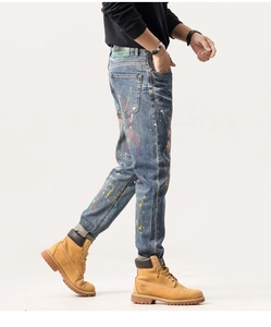 Détail de jean bleu ajusté avec éclaboussures de peinture colorées et écusson en cuir au dos