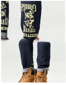 Détails de broderie jaune avec crâne et lettrage sur un jean droit en denim bleu