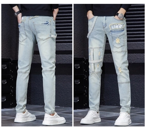 Detail of light blue distressed slim fit jeans with rip-and-repair patches and LSKE tag
