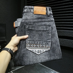 Détail d'un jean gris foncé montrant une broderie ethnique sur la poche arrière