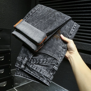 Détail du denim gris délavé avec coutures contrastées oranges et broderies graffiti