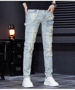 Close-up of men's blue slim fit jeans featuring patch details and stylish ripped knee elements