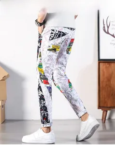 Detailed view of white street-style pants with money and graffiti prints on a male model