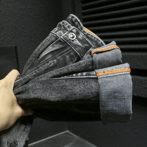 Détail du jean gris foncé délavé avec bouton en métal vintage et lisière selvedge orange