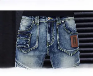Détail de la taille avec bouton métallique et patch en cuir sur jean denim délavé