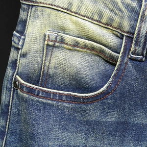 Men's blue denim jeans featuring vintage yellow wash and orange contrast stitching