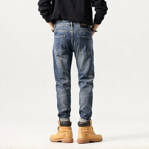 Men's slim-fit washed blue jeans with back embroidery, patch details, and metal buckle accent