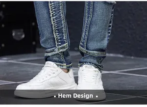 Détail de l'ourlet effiloché et du design patchwork sur un jean bleu délavé