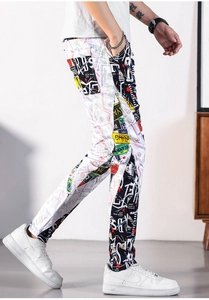 Detailed view of men's slim fit graffiti jeans with US dollar print and street style patches
