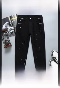 Gros plan sur un jean noir avec des détails de taches de peinture bleues et blanches