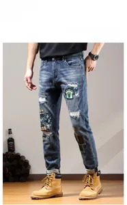 Close-up of men's distressed slim jeans with patchwork details and embroidery