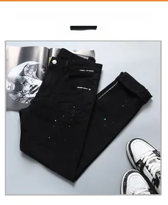 Gros plan sur le jean noir avec des taches de peinture bleue et blanche et ourlet rouge