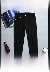 Détails de jeans noirs coupe ajustée avec effets de déchirure et bouton métallique