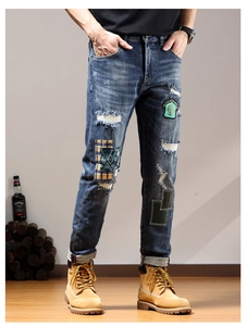 Detailed close-up of blue slim-fit distressed jeans with colorful embroidery patches