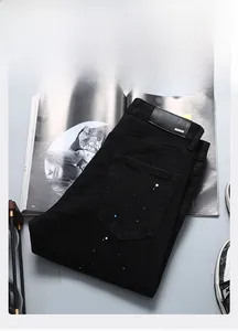 Détail du jean slim noir avec motif de peinture par projection et étiquette arrière en cuir