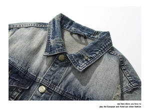 Detail of vintage blue denim jacket showing collar fraying and metal buttons with engraving
