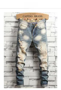Close-up of distressed light blue denim jeans with heavy wash and ripped knee details