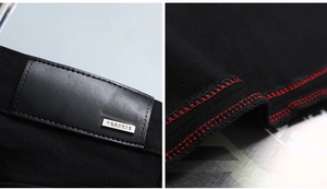 Détail du denim noir avec surpiqûres rouges et plaque de marque en cuir
