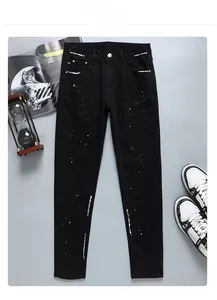 Gros plan d'un jean slim noir avec des détails de taches de peinture industrielle blanche