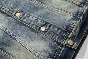 Macro detail of retro washed blue denim jacket with vintage copper buttons and stitching