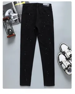 Détail des poches arrière d'un jean noir slim avec des éclaboussures de peinture bleue et blanche