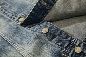 Macro detail of retro metal button and heavy washed denim texture on blue jacket