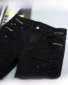 Gros plan d'un jean slim noir avec détails de taches de peinture bleues et blanches