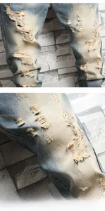 Detail of ripped light blue vintage denim jeans with distressed texture and fraying