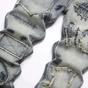 Jean flare homme bleu délavé avec détails effilochés et broderies ondulées noires