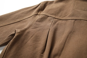 Detailed close-up of heavy-duty brown canvas jacket with reinforced double-needle stitching