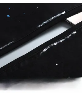 Gros plan sur tissu denim noir avec des éclaboussures de peinture blanche et bleue