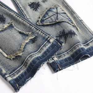 Jeans évasés bleu délavé avec broderie en croix et détails de patchwork usés