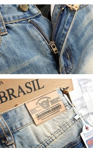 Detail of vintage washed blue jeans featuring metal buttons and leather brand patch on waist