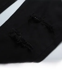 Gros plan sur un jean noir usé avec des déchirures tendance et des détails en strass