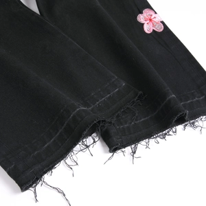 Men's black flare jeans featuring pink flower embroidery and trendy raw edge hems
