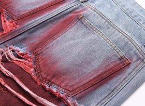 Détail du denim dégradé coloré avec des trous effilochés et des doubles surpiqûres