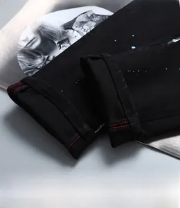 Détail d'éclaboussures de peinture bleue et blanche sur jean noir à coutures rouges