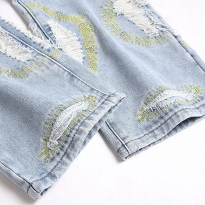 Slim fit light blue distressed jeans with yellow star embroidery and ripped hem details