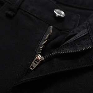 Vue rapprochée du jean noir slim avec fermeture éclair YKK de qualité et bouton en métal