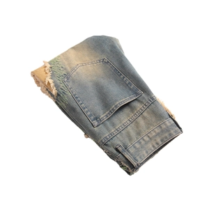 Vintage wash blue denim jeans with distressed holes and green zigzag stitching details