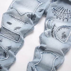 Men's light blue flared jeans with distressed graffiti patches and high street embroidery