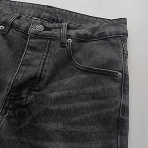 Detail of waist area showing metal button and washed denim texture on vintage jeans