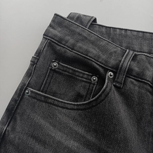 Detail of dark grey washed denim waist with silver rivets and durable stitching
