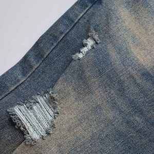 Detalle de denim desgastado que muestra bordes deshilachados y textura de lavado vintage