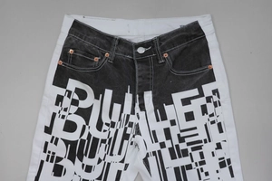 Detail of high-contrast black and white patchwork jeans with bold white printed lettering