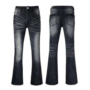 Detail view of faded black flare jeans with paint splatter and vintage wash texture