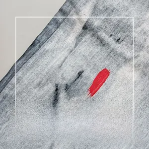 Close-up of marble wash denim fabric with red paint strokes and high elasticity texture