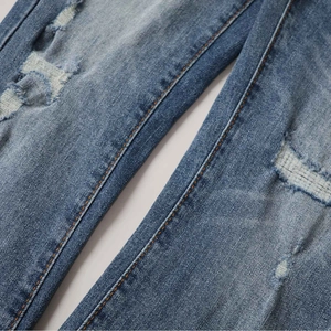 Detailed macro view of distressed blue denim jeans with hand-made ripped hole effects