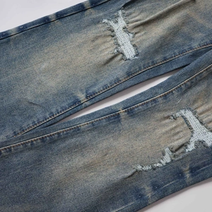 Detalle del de la rodilla con bordado en vaqueros denim índigo vintage efecto gastado
